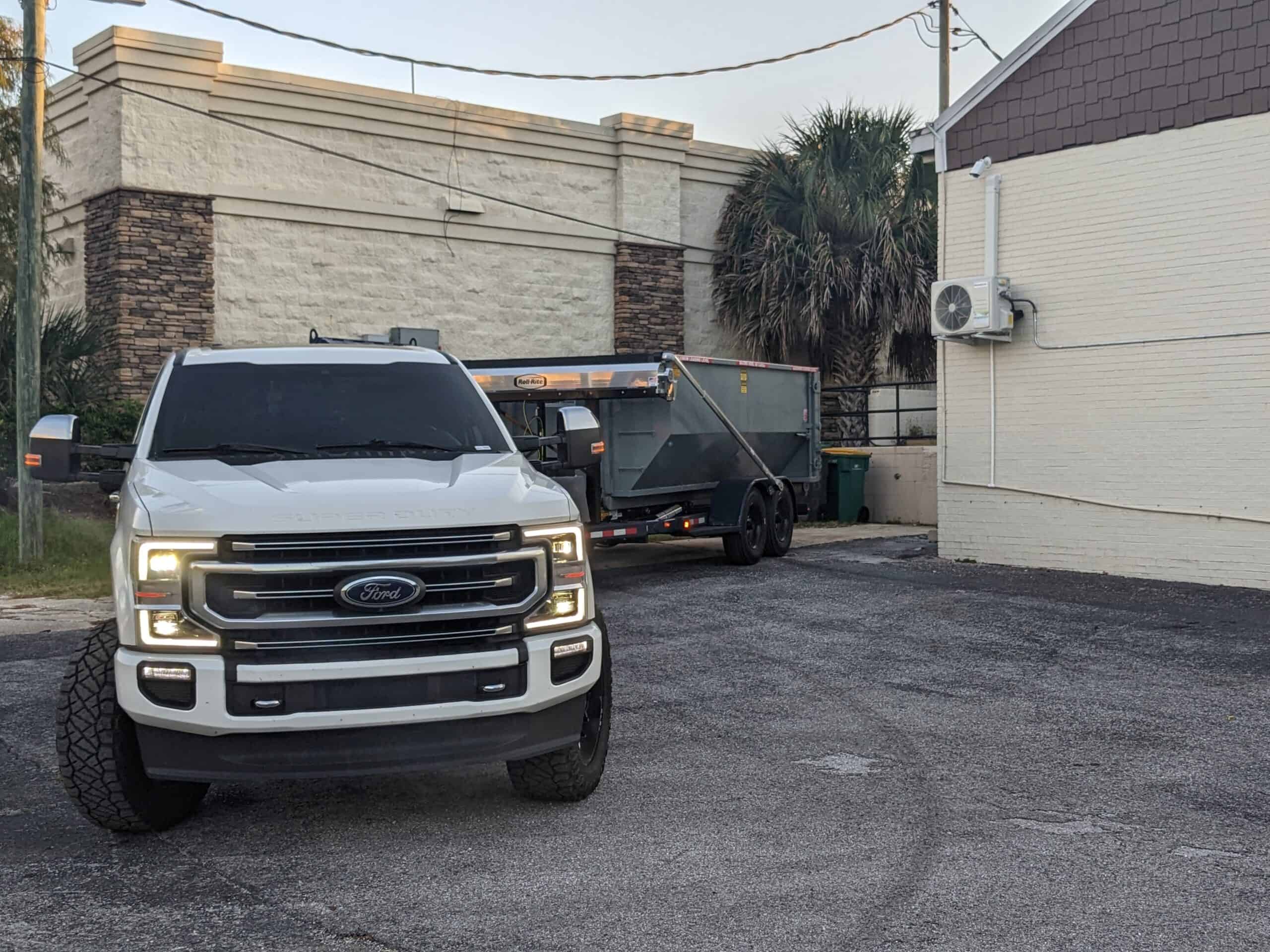 PXL 20221010 114725457 scaled - Yankee Dumpster LLC White work truck pulling an empty Yankee Dumpster dumpster behind commercial building in Wekiwa Springs, FL
