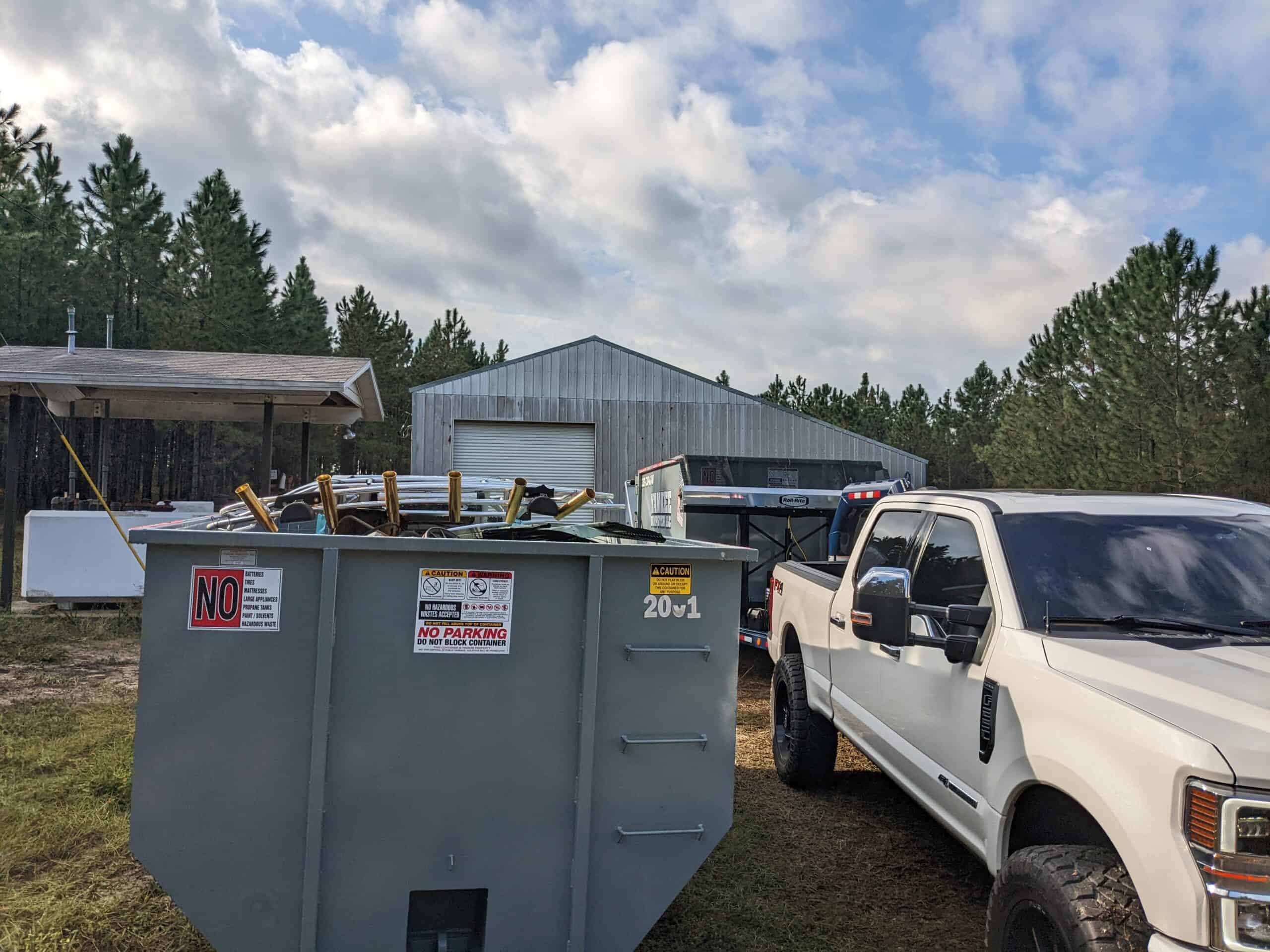 Yankee Dumpster dumpster filled with debris next to white truck pulling second dumpster in front of silver shed in Winter Park, FL