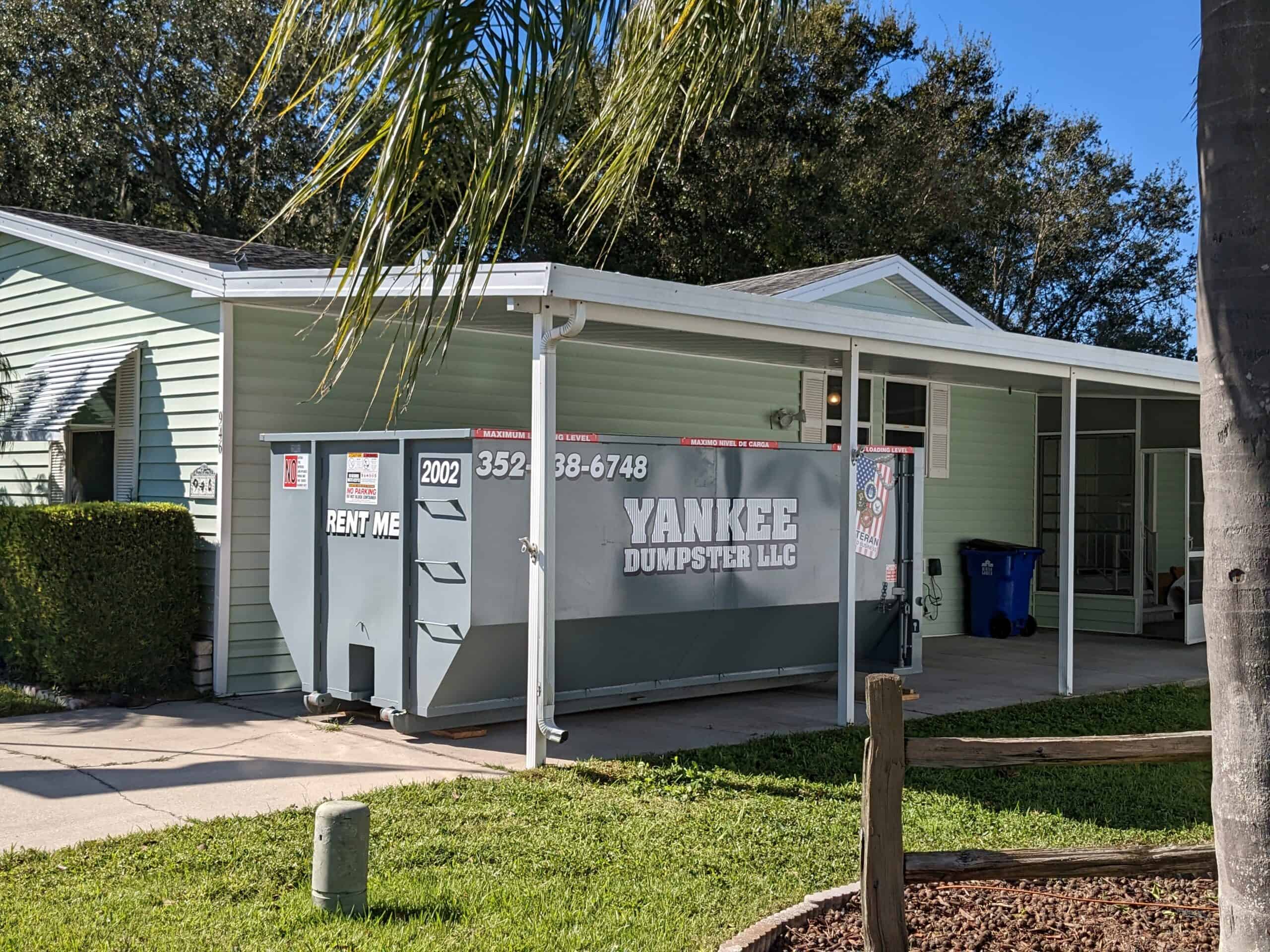 Grey Yankee dumpster parked underneath home car port on the side of the home in Clermont, FL